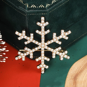 Close-up of snowflake brooch with white rhinestones on gold alloy base for Christmas