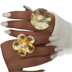 Exaggerated gold-tone adjustable flower and disk rings with white pearls on hand