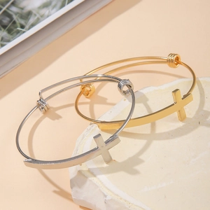 Detail of gold and silver cross bangles on stone pedestals with minimalist design