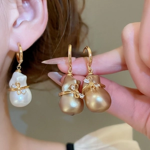 Détails des boucles d'oreilles perles baroques avec nœud doré et détails de diamants