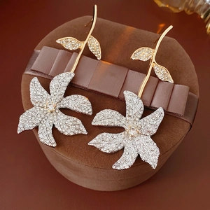Floral silver needle earrings with pave diamonds and gold accents on velvet display