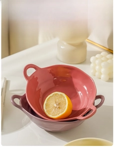 Close-up of pink and purple ceramic bowls with side handles and fresh lemons