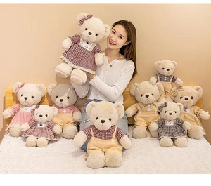 Detail of assorted teddy bears in checkered outfits held by model in warm bedroom setting