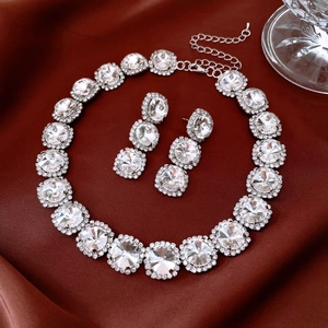 Detail view of crystal pendant earrings and necklace set on vintage red satin fabric