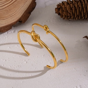 Minimalistisches goldenes Knot-Armband Set auf strukturiertem Naturstein-Hintergrund