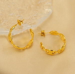Close-up of gold titanium steel pig nose hoop earrings on champagne textured background