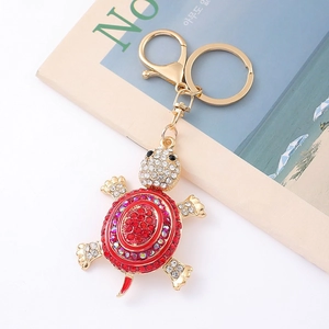 Macro detail of a red crystal turtle keychain with gold hardware and sparkling rhinestones