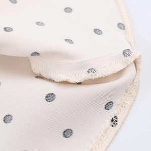 Detail view of the fine stitching and neat edge finish on white polka dot satin fabric