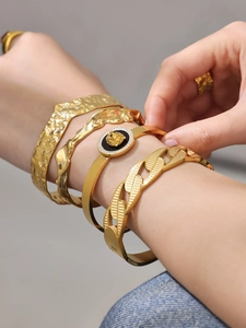 Detail of 18k gold plated hammered bangles featuring lion head coin and chunky chain style