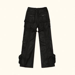 Macro detail of black waxed canvas cargo pants showing back pockets and industrial straps