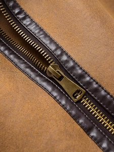 Detail of bronze metal zipper with leather trim on a vintage fleece brown vest