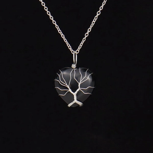 Close-up of heart-shaped black stone pendant with silver wire-wrapped tree of life