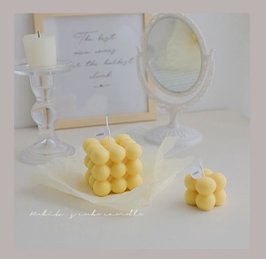 Detail of two yellow bubble cube candles in different sizes with a matte wax finish