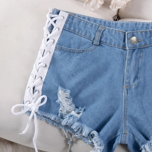 Dettaglio di pantaloncini in denim azzurro con lacci laterali e finitura dell'orlo sfrangiato