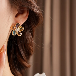 Close-up of elegant flower stud earring with colorful zircon stones worn by a model