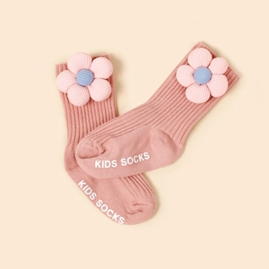 Détail de chaussettes bébé côtelées roses avec fleur 3D et semelle antidérapante