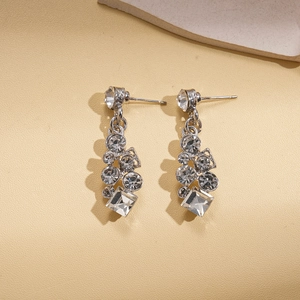Gros plan détaillé des boucles d'oreilles argentées avec cristaux carrés et strass brillants