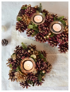 Macro shot of a Christmas candle holder with red pine cones, pine needles and glass cup