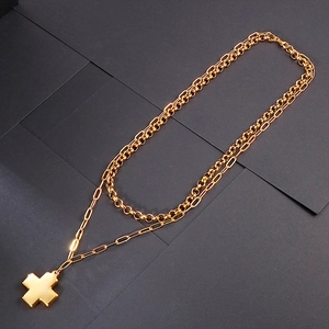 Double-layered gold stainless steel necklace with a minimalist cross pendant on grey background