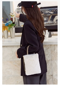 White plush crossbody bag with gold chain strap shown styled on a black blazer jacket