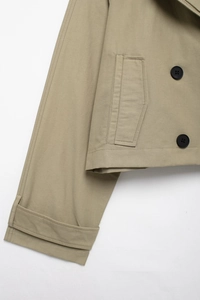 Close-up of khaki trench jacket featuring black buttons and adjustable cuff straps