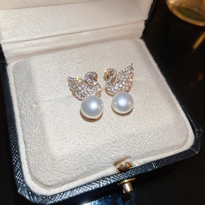 Detailed view of elegant gold-plated swan pearl earrings with sparkling crystal accents