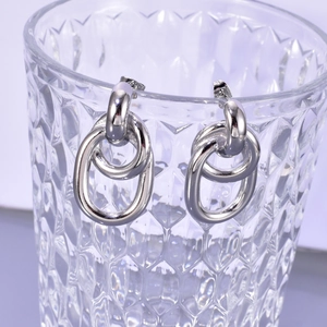 Détail de boucles d'oreilles double cercle argentées sur un bord en verre