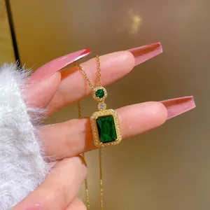 Close-up of gold titanium necklace with emerald cut green gemstone and micro-pave diamonds