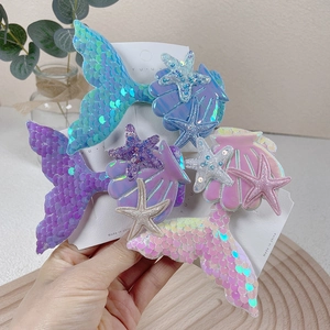 Detail view of sequined mermaid tail, starfish, and shell hair clips in pastel gradients