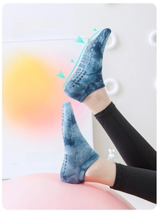 Close-up of blue tie-dye yoga socks showing full-palm silicone non-slip dots on a gym ball