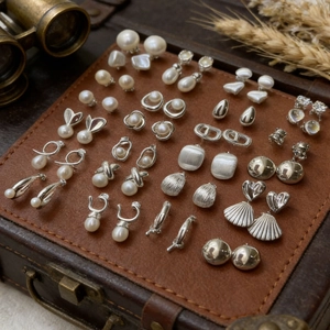Detailed collection of pearl and geometric earrings displayed on a vintage leather case