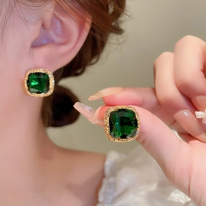 Detailed view of emerald green square zircon stud earrings with gold textured frame