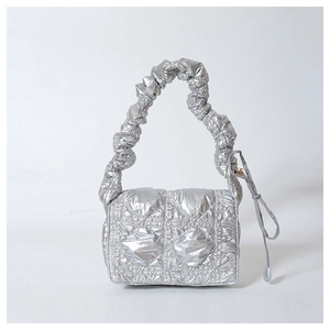 Detailed view of silver metallic quilted handbag with ruched handle and puffer texture