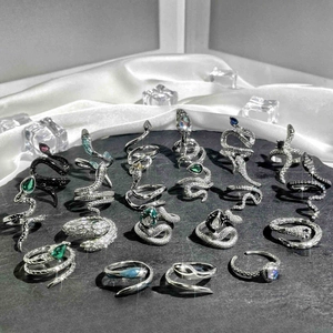 Detailed group of punk snake rings with green and blue crystals on white silk