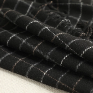 Close-up of soft black plaid cashmere-like scarf fabric with brown grid and fringe detail