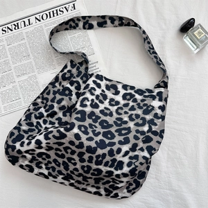 Flat lay of leopard print canvas tote bag with fashion props on white fabric