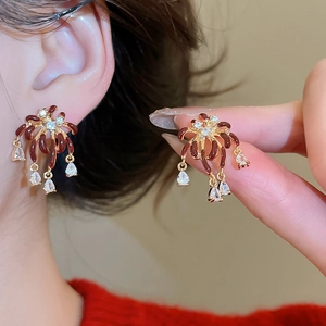 Close-up of gold-plated firework earrings with red enamel and zircon droplets