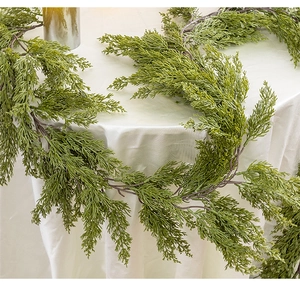 Close-up of artificial cypress garland with realistic pine needles on white fabric
