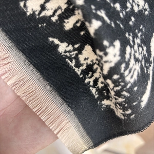 Close-up detail of cashmere-like scarf showing houndstooth weave and fringed tassel edges
