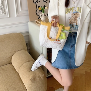 Detailed embroidery of cartoon dog and carrot on a white quilted handbag with yellow handle