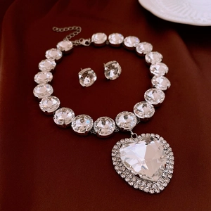 Detail of silver crystal jewelry set with heart pendant on red velvet background