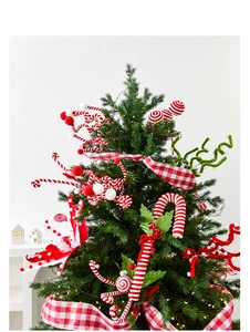 Detail of red and white striped candy cane picks and plaid ribbons on a lush green Christmas tree
