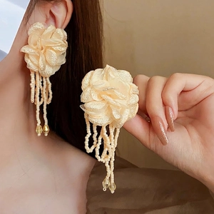 Elegant floral tassel earrings with fabric petals and delicate seed beads on model