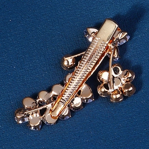 Detailed close-up of the golden metal spring clip and crystal flower design on hair clip