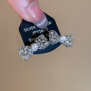 Dettaglio di un fermaglio per capelli a fiocco argento con strass lucidi e perle bianche