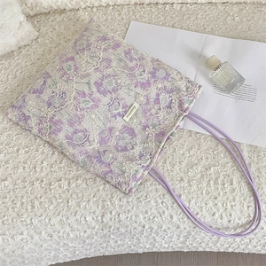 Close-up of floral tote bag with white lace crochet overlay and purple top handles