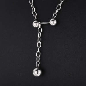 Vue détaillée du collier pendentif haltère argenté avec fermoir en T et breloques boules