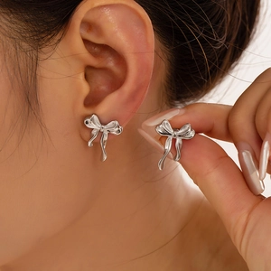 Elegant silver bow-shaped titanium steel earrings worn by model in a stylish close-up view