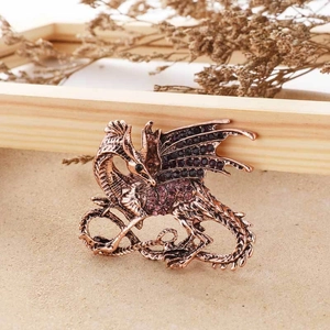 Detail of vintage bronze dragon brooch with purple and black rhinestones on a warm background