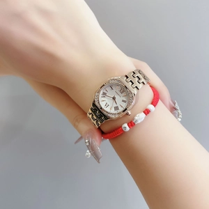 Detail of square gold quartz watch with rhinestone bezel and roman numeral white dial